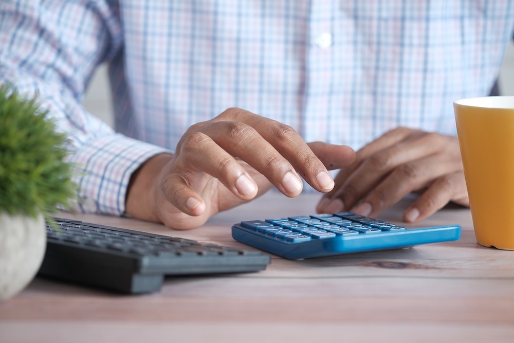 Man typing on calculator seeing how it makes sense to go with commercial solar sustainability